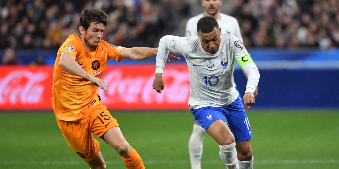 Marten de Roon laat zich aftroeven door Kylian Mbappé tijdens Frankrijk - Nederland. Beide spelers zullen er in de EK-wedstrijd niet bij zijn.