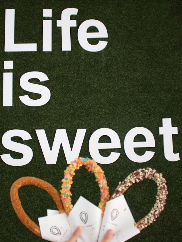 Three churros from the Loop next to their grass wall that says
