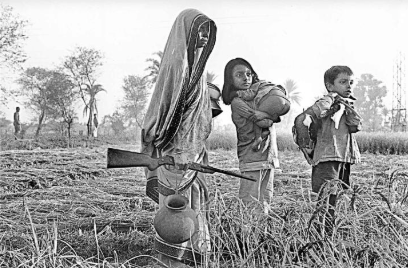 A woman emerges from hiding for the first time, carrying a rifle and accompanied by her children. The family were hiding from Pakistani troops in 1971, near Jessore, Source: Bangladesh (UNB), Voice of International Affairs.