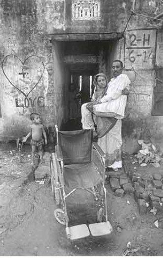 Farid Mian, a wounded freedom fighter of the Bangladesh Liberation War, is being carried to a wheelchair by his wife, Source: Drik, Photo by Abir Abdullah
