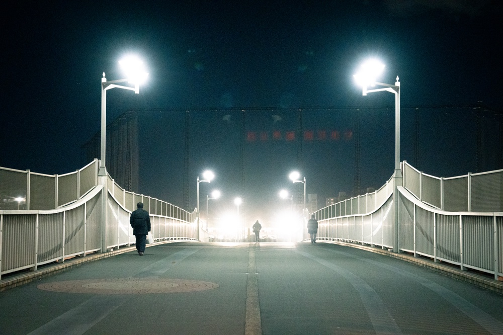 奥にゴルフの打ちっぱなしがあって、すごい光量で照らされている歩道橋